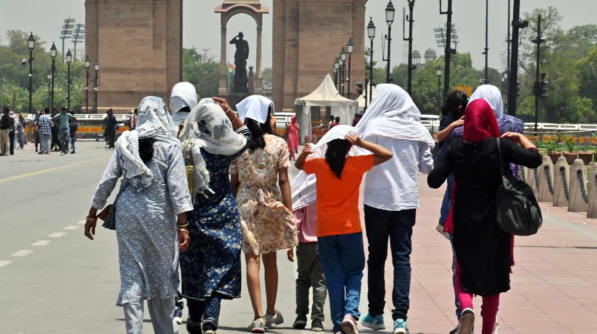 People walk on Kartavya Path near India while covering themselves to protect from the scorching heat
