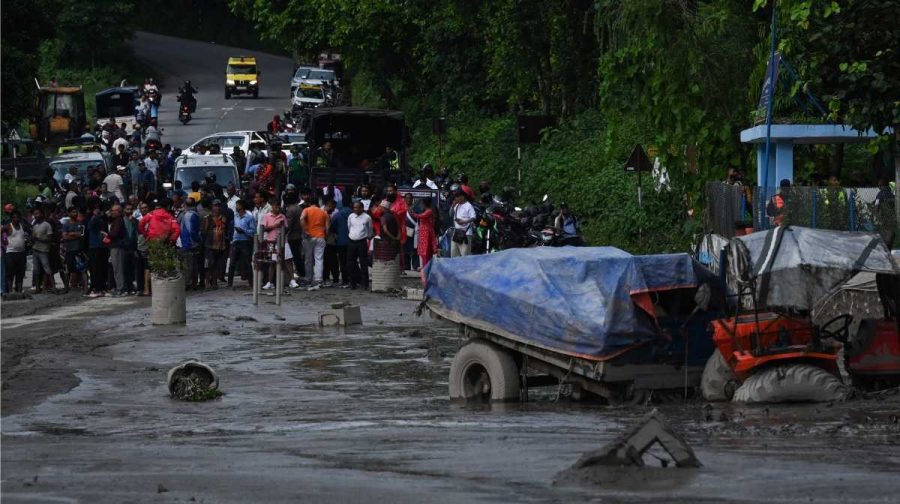 Residents look at buildings and street submerged by mud following flash floods and a landslide disaster in Devighat, in Nepal's Nuwakot district on August 26, 2026. A massive flood and landslide disaster on the Nepal-Tibet border killed at least 103 people on August 26, 2026 and left several hundred missing, many of them foreign tourists. Aid workers said entire settlements had been "wiped out". Some 403 tourists -- 341 of them foreigners -- were unaccounted for several hours after the disaster struck, according to the tourism ministry. (Photo by PRAKASH MATHEMA / AFP)