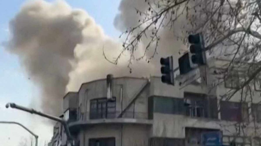 This video grab taken from UGC images posted on social media on February 28, 2026, and verified by AFPTV teams in Paris, shows a man looking on as a plume of smoke rises following a repoted explosion in Tehran. Two loud blasts were heard in Tehran on February 28 morning by AFP journalists, and two plumes of thick smoke were seen over the centre and east of the Iranian capital. Israel's defence ministry announced it had launched a "preemptive strike" on Iran as sirens sounded in Jerusalem and people across the country received phone alerts about an "extremely serious" threat. (Photo by various sources / AFP) / - Israel OUT / RESTRICTED TO EDITORIAL USE - MANDATORY CREDIT AFP -  SOURCE: UGC / UNKNOWN - DISTRIBUTED AS A SERVICE TO CLIENTS - NO RESALE - NO ACCESS ISRAEL MEDIA/PERSIAN LANGUAGE TV STATIONS OUTSIDE IRAN/ STRICTLY NO ACCESS BBC PERSIAN/ VOA PERSIAN/ MANOTO-1 TV/ IRAN INTERNATIONAL/RADIO FARDA - AFP IS NOT RESPONSIBLE FOR ANY DIGITAL ALTERATIONS TO THE PICTURE'S EDITORIAL CONTENT / 