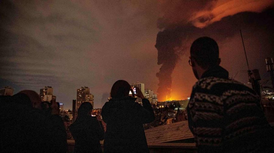 Residents watch and take pictures as flames and smoke rise from an oil storage facility struck as attacks hit the city during the U.S.Israeli military campaign in Tehran, Iran, Saturday, March 7, 2026. (Alireza Sotakbar/ISNA via AP)