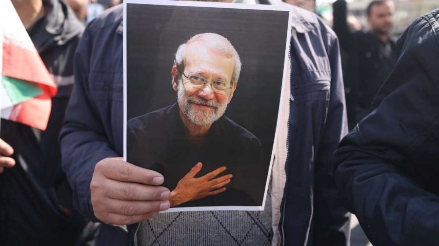 A mourner holds a picture of Iran's security chief Ali Larijani during his funeral alongside Gholamreza Soleimani, a senior officer in the Islamic Revolutionary Guard Corps who commands Basij forces, in Tehran on March 18, 2026. After crowds gathered in central Tehran for the funeral of Iran's security chief Ali Larijani, Iran's new supreme leader Mojtaba Khamenei declared in a written message that his killers would pay. Larijani's funeral was held alongside those of Gholamreza Soleimani, the head of the Basij paramilitary force who was also killed in a strike in Iran this week, and dozens of Iranian sailors who were killed when US forces torpedoed their frigate off Sri Lanka earlier this month. (Photo by ATTA KENARE / AFP) /