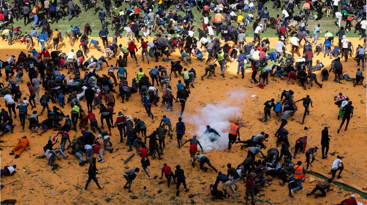 Supporters and mourners of Kenyan opposition leader Raila Odinga run for cover after gunshots and teargas were fired during a gathering for the public viewing of his coffin at the Kasarani Stadium in Nairobi on October 16, 2025 following Odinga's death at the age of 80 during a health visit to India. Tens of thousands of mourners fled in panic as police fired gunshots and teargas in a stadium where they had gathered to see the coffin of opposition leader Raila Odinga, whose body was repatriated from India on October 16, 2025. (Photo by Kabir Dhanji / AFP)