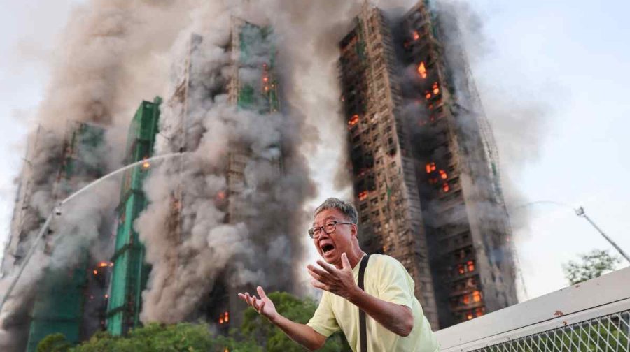A man reacts, as smoke rises while flames engulf bamboo scaffolding across multiple buildings at Wang Fuk Court housing estate, in Tai Po, Hong Kong, China, November 26, 2025. REUTERS/Tyrone Siu