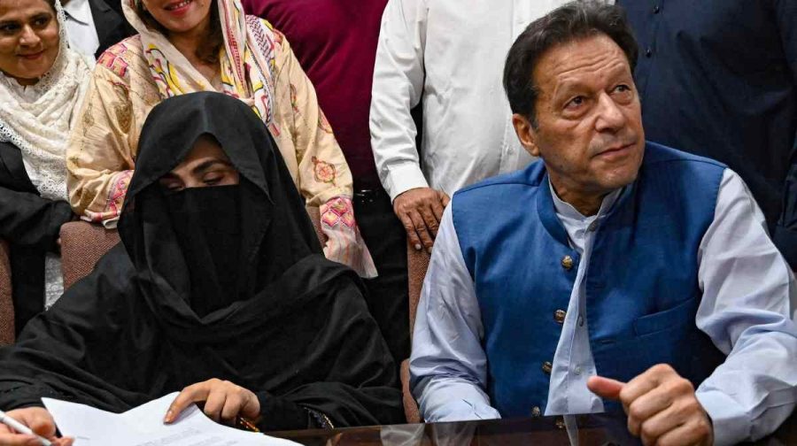 Pakistan's former Prime Minister, Imran Khan (R) along with his wife Bushra Bibi (L) looks on as he signs surety bonds for bail in various cases, at a registrar office in the High court, in Lahore on July 17, 2023. Former Pakistan Prime Minister Imran Khan and his wife were sentenced on January 31, 2024, to 14 years in jail, local media said, after being found guilty of graft in a case involving gifts he received while premier. (Photo by Arif ALI / AFP)