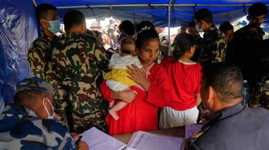 A woman and her child rescued from an area cut off by flash flooding stands for registration in Nepal's Nuwakot district, Saturday, Aug. 29, 2026. (AP Photo/Dar Yasin)