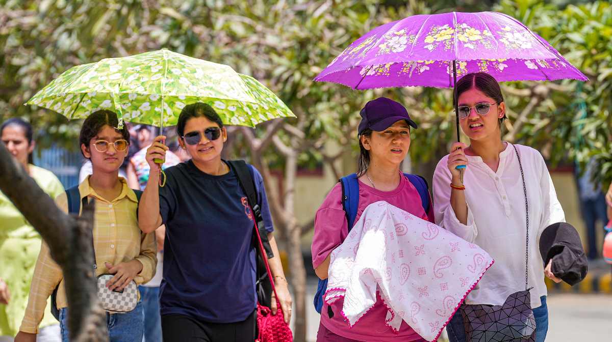 New Delhi: Women walk under umbrellas on a hot summer day, in New Delhi, Wednesday, June 11, 2025. The India Meteorological Department (IMD) on Monday issued an orange alert for the capital city till Wednesday, warning people to stay cautious and take steps to protect themselves from the ongoing heatwave. (PTI Photo/Kamal Singh)  (PTI06_11_2025_000131B)