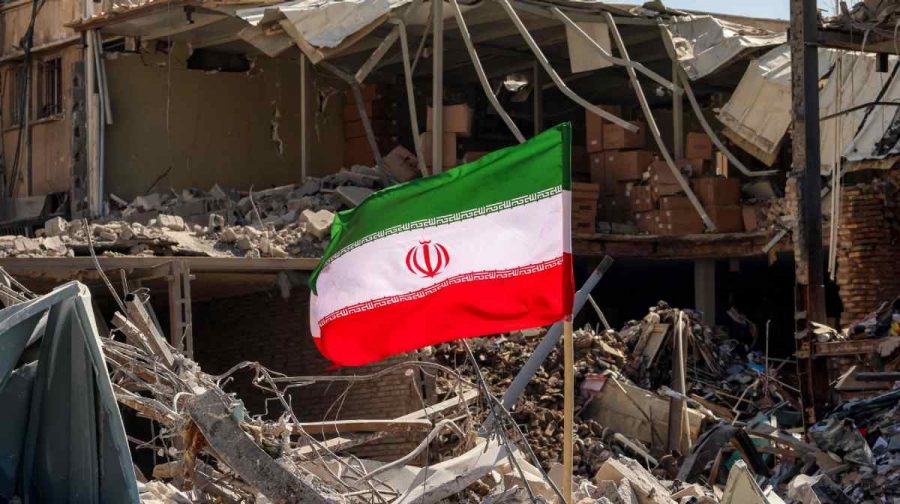 TOPSHOT - An Iranian flag is placed amids rubble and debris next to a destroyed residential building near Ferdowsi square in Tehran on March 3, 2026. The United States and Israel started striking Iran on February 28, killing Iran's supreme leader and top military leaders, and prompting authorities to retaliate with strikes on Israel and across the Gulf. (Photo by ATTA KENARE / AFP)