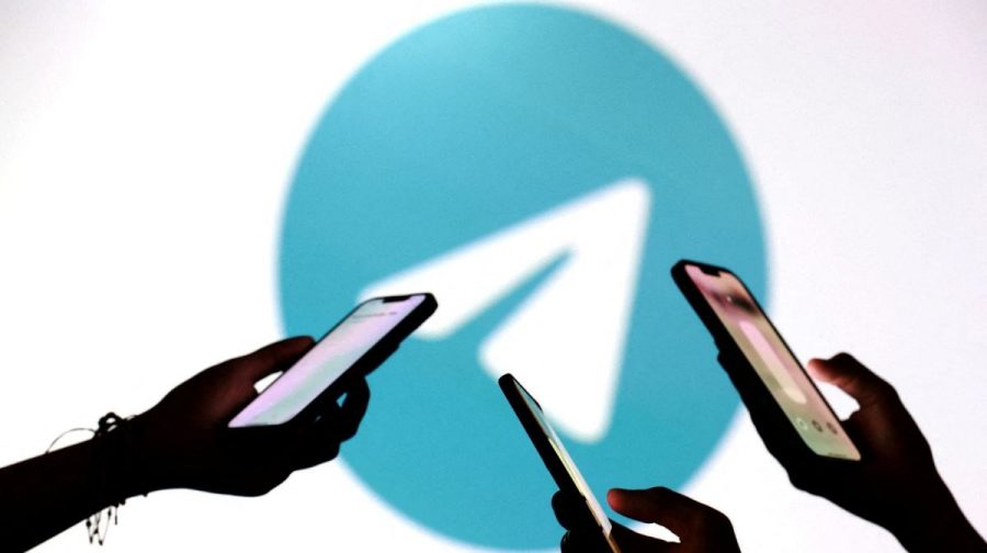 FILE PHOTO: Teenagers pose for a photo while holding smartphones in front of a Telegram logo in this illustration taken September 11, 2025. REUTERS/Dado Ruvic/Illustration/File Photo