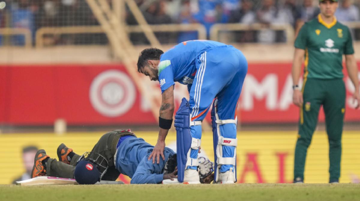 Virat Kohli being greeted by a pitch invader as he completes his century during the first ODI cricket match of a series between India and South Africa (PTI Photo/Kamal Kishore)