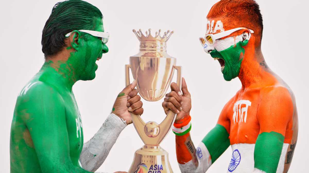 Two Indian cricket fans, with their bodies painted in the colors of Indian and Pakistan flags, pose for the media with a cutout image of the Asia Cup trophy in Ahmedabad, India on the eve of the Asia Cup match between the two countries, Saturday, Sept. 13, 2025. (AP Photo/Ajit Solanki)