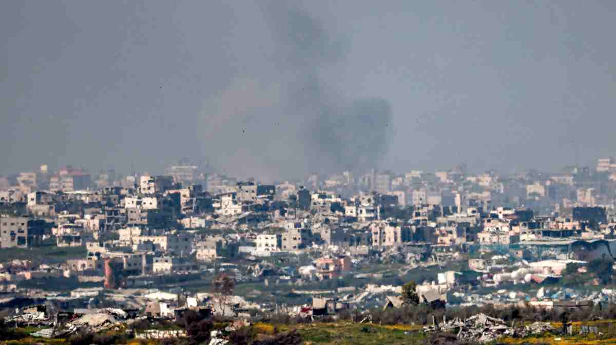 A cloud of smoke billows as destroyed buildings are pictured in the northern Gaza Strip from across the border in southern Israel on March 18, 2025. Israel on March 18 unleashed its most intense strikes on the Gaza Strip since a January ceasefire, with rescuers reporting 220 people killed, and Hamas accusing Benjamin Netanyahu of deciding to "resume war" after a deadlock on extending the truce. (Photo by Menahem KAHANA / AFP)