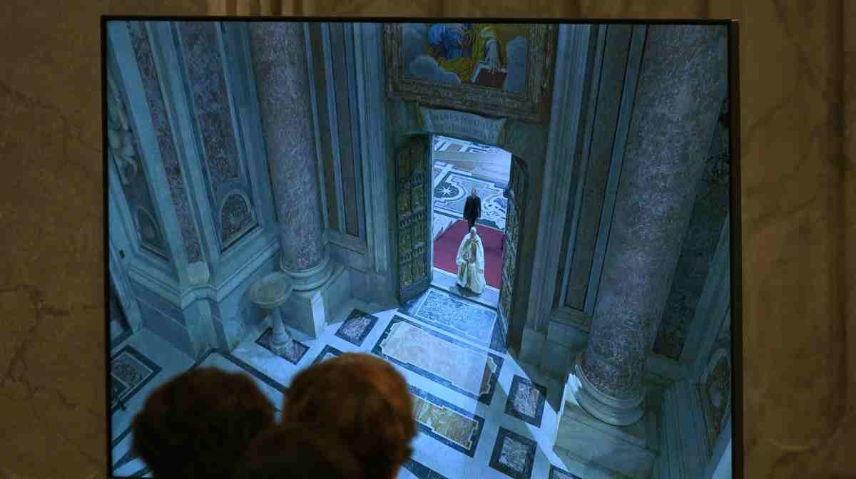 People watch a screen displaying images of Pope Francis opening the Holy Door before the Christmas Eve mass at St Peter's Basilica in the Vatican on December 24, 2024.