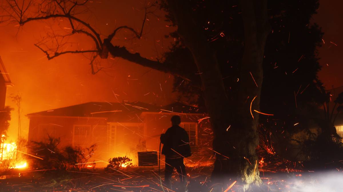 A person tries to hose down embers from the Palisades Fire in the Pacific Palisades neighborhood of Los Angeles | AP Photo