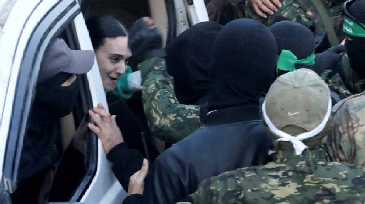 Palestinian Hamas militants gather around a vehicle during a handover of hostages | REUTERS/Dawoud Abu Alkas
