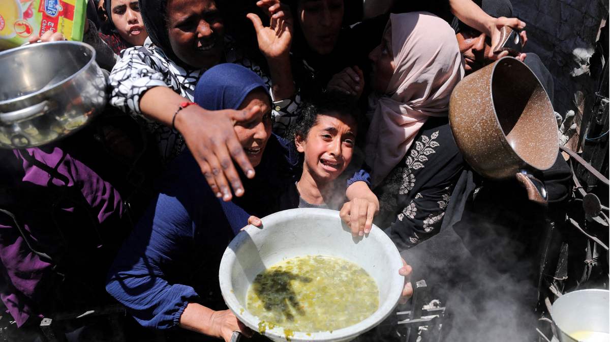 FILE PHOTO: A Palestinian receives food cooked by a charity kitchen, in Beit Lahia, northern Gaza Strip, May 8, 2025. REUTERS/Mahmoud Issa/File Photo NO RESALES. NO ARCHIVES.