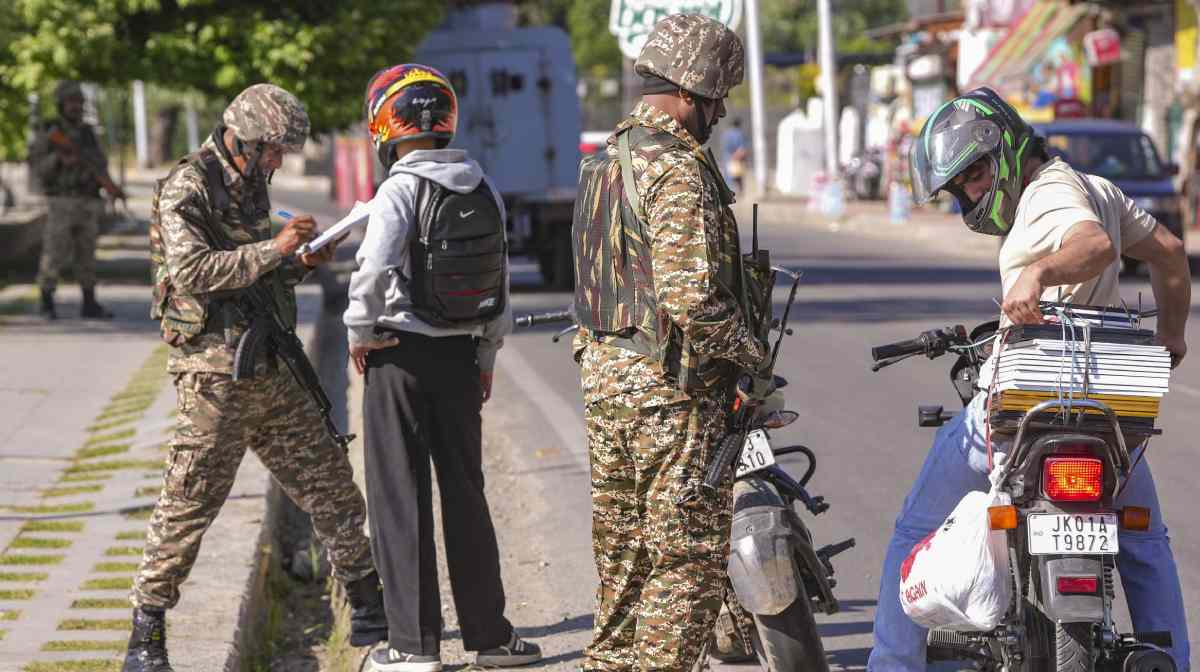 Security personnel check identity cards of commuters