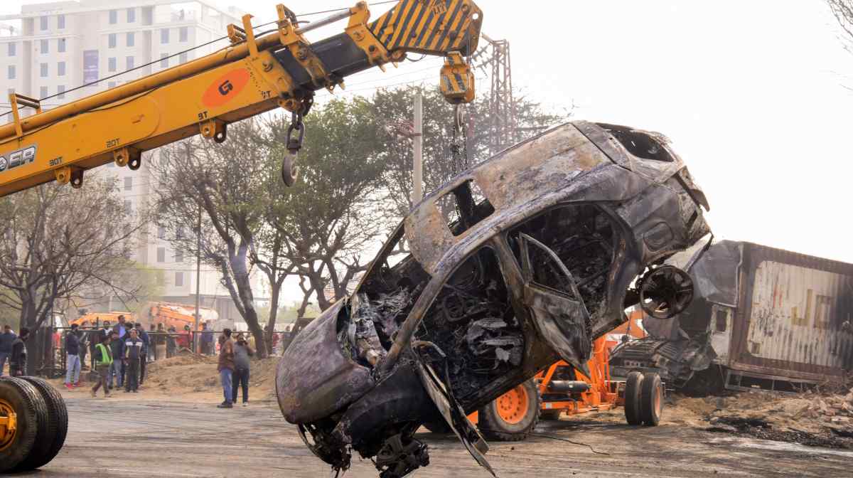 A crane carries the charred remains of a car at the site of the accident after a massive fire started due to a collision between a gas tanker and multiple vehicles near a petrol pump on the Jaipur-Ajmer Highway, in Jaipur on Friday. 