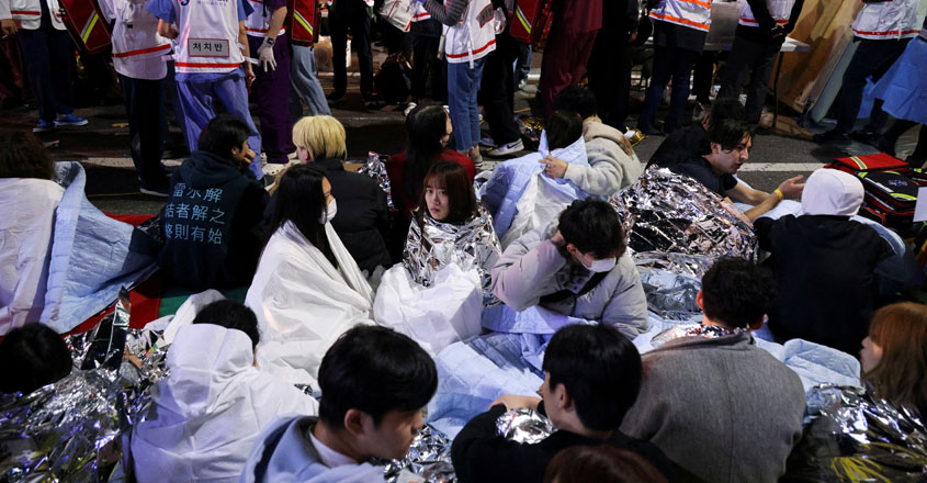 People sit on the street after being rescued, at the scene where dozens of people were injured in a stampede during a Halloween festival in Seoul, South Korea, October 30, 2022. REUTERS/Kim Hong-ji REFILE - CORRECTING DATE