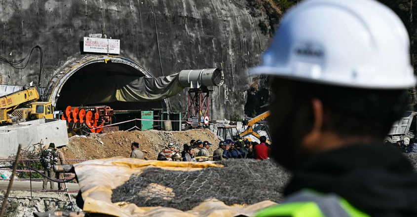 A rescue personnel stands near an entrance of the Silkyara under construction road tunnel, during the final phase of a rescue operation, days after a portion of it collapsed in the Uttarkashi district of India's Uttarakhand state on November 23, 2023. Ambulances were on standby on November 23 morning, as Indian rescuers dug through the final metres of debris separating them from 41 workers trapped in a collapsed road tunnel for nearly two weeks. (Photo by Arun SANKAR / AFP)