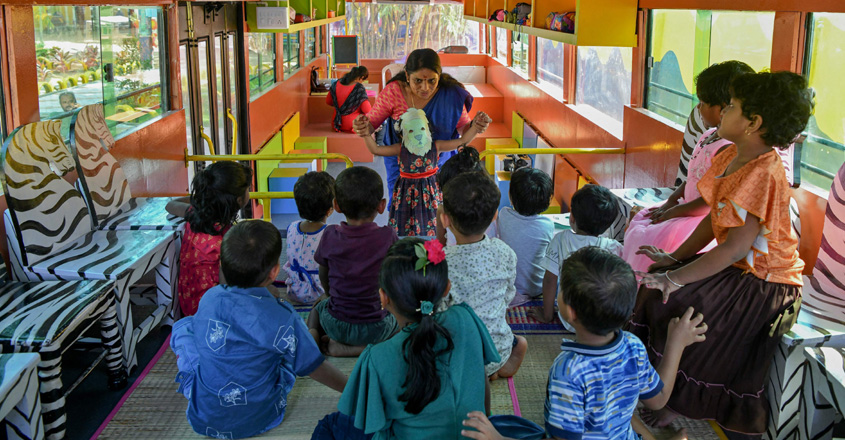 A teacher engages her pupils in an activity inside a re-modified low-floor old defunct public transport bus transformed into a classroom for pre-nursery school children through an initiative 'Education on Wheels' taken by the state government at Thiruvananthapuram in India's Kerala state on June 13, 2022. (Photo by Manjunath Kiran / AFP)