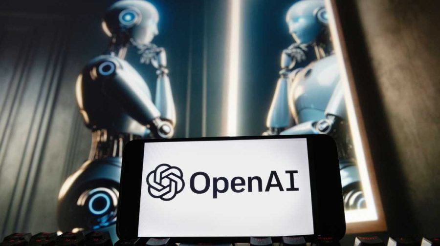 FILE - The OpenAI logo is displayed on a cellphone with an image on a computer monitor generated by ChatGPT's Dall-E text-to-image model, Dec. 8, 2023, in Boston. (AP Photo/Michael Dwyer, File)